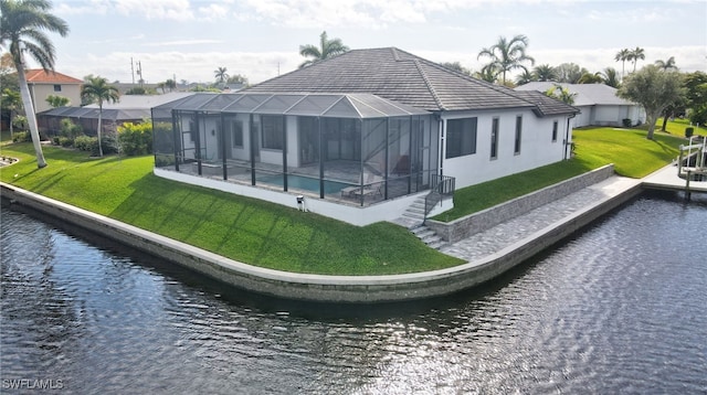 back of house with a yard, a water view, and a lanai