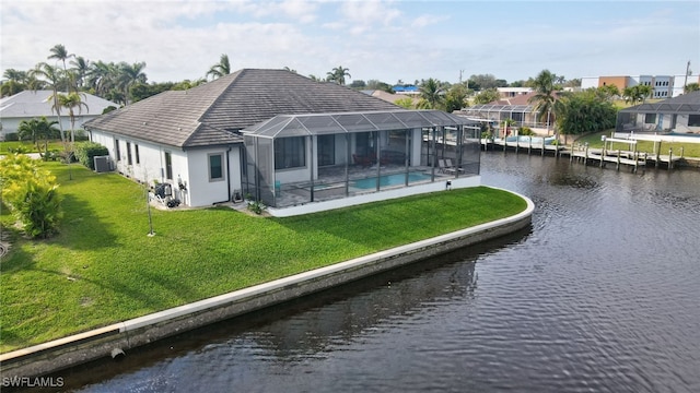 rear view of property with a lanai, a water view, a lawn, and central AC