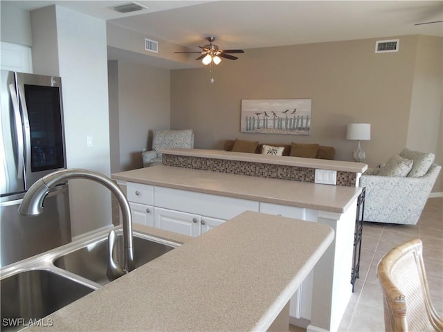 kitchen featuring ceiling fan, a center island, sink, light tile patterned floors, and white cabinets