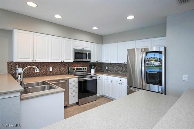 16590 Crownsbury Way Unit 102, Fort Myers, FL 33908 - kitchen with white cabinetry, light tile patterned floors, backsplash, a sink, and appliances with stainless steel finishes