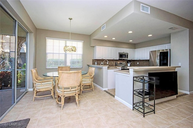 16590 Crownsbury Way Unit 102, Fort Myers, FL 33908 - kitchen with a peninsula, stainless steel appliances, light tile patterned floors, visible vents, and decorative backsplash