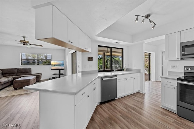 kitchen featuring kitchen peninsula, white cabinetry, light wood-type flooring, and appliances with stainless steel finishes