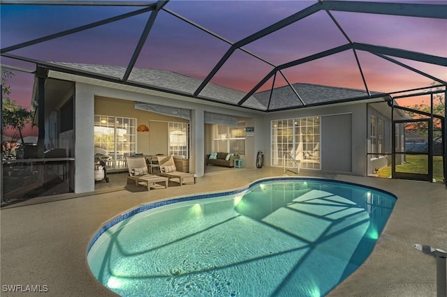 pool at dusk with a patio and glass enclosure