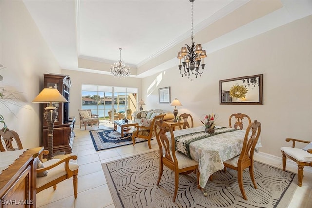 dining area with a water view, crown molding, light tile patterned floors, a tray ceiling, and a notable chandelier