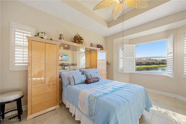 bedroom with light tile patterned floors, a water view, a raised ceiling, and ceiling fan