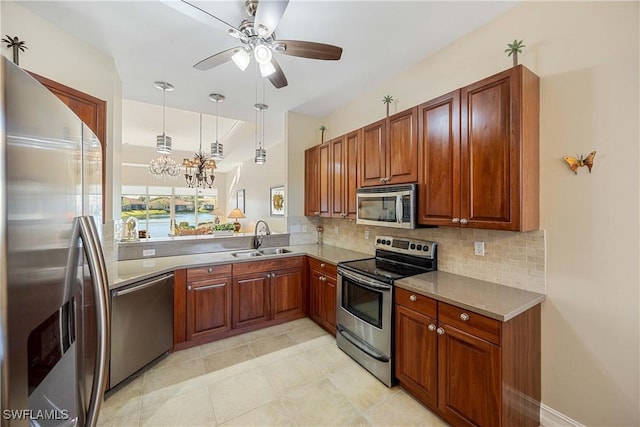 kitchen featuring decorative backsplash, ceiling fan with notable chandelier, stainless steel appliances, sink, and pendant lighting