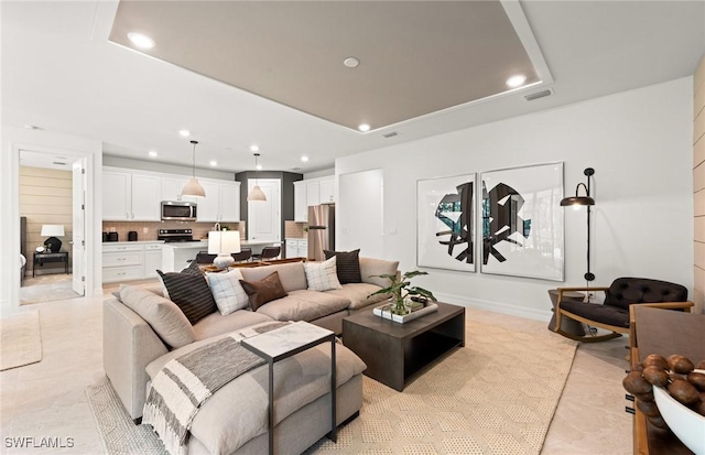 living room with a tray ceiling and light tile patterned floors