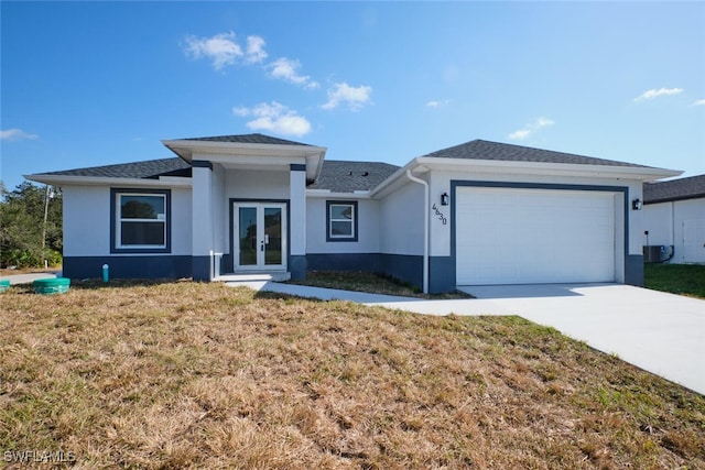 view of front facade with central air condition unit, french doors, a front yard, and a garage