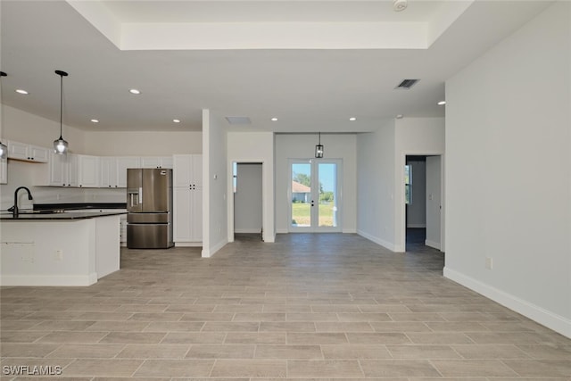 kitchen featuring french doors, sink, stainless steel refrigerator with ice dispenser, hanging light fixtures, and white cabinetry