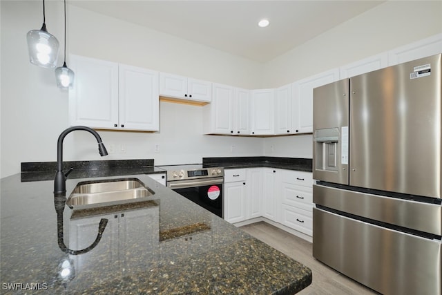 kitchen with white cabinets, sink, hanging light fixtures, dark stone countertops, and stainless steel appliances