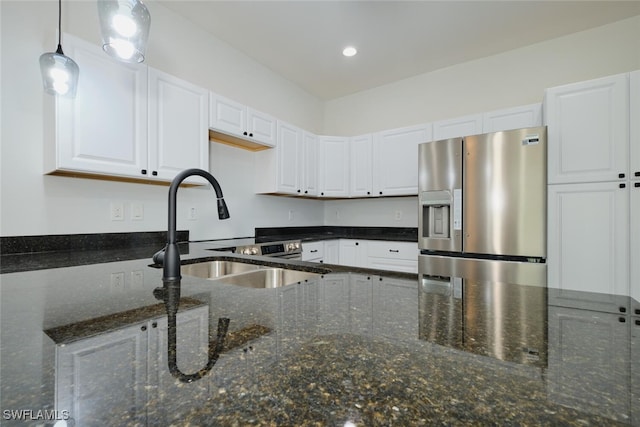 kitchen with sink, dark stone countertops, stainless steel fridge, pendant lighting, and white cabinets