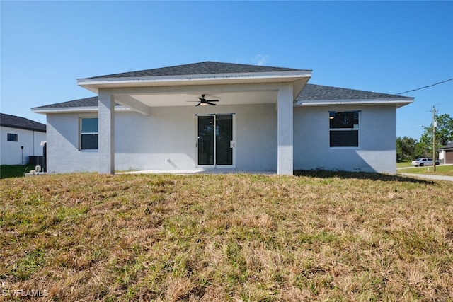 back of property featuring ceiling fan and a yard