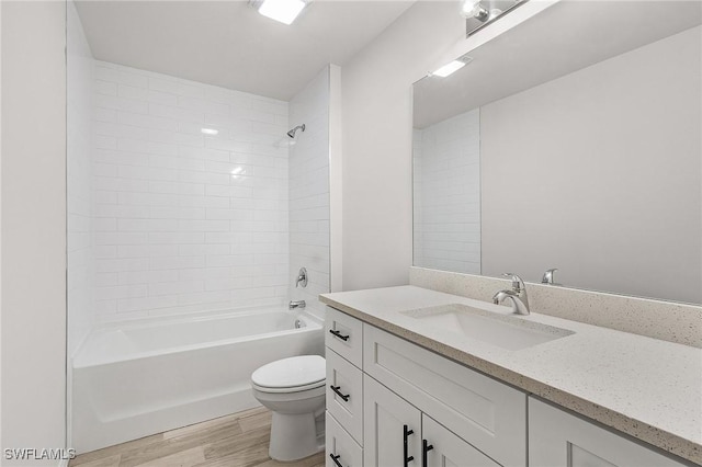 full bathroom with vanity, wood-type flooring, tiled shower / bath combo, and toilet