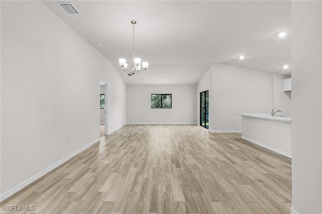 unfurnished living room featuring a chandelier, light hardwood / wood-style floors, and lofted ceiling