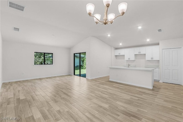 unfurnished living room with a notable chandelier, light wood-type flooring, sink, and lofted ceiling