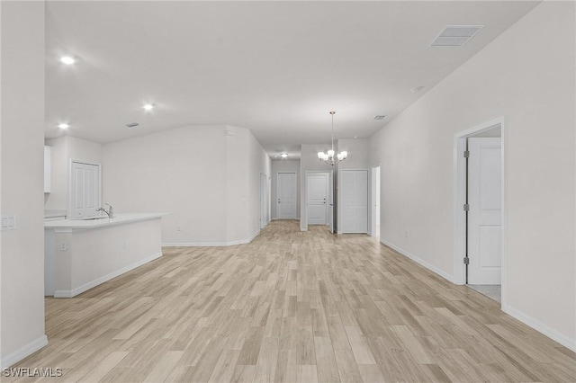 unfurnished living room featuring light hardwood / wood-style floors, a notable chandelier, and sink