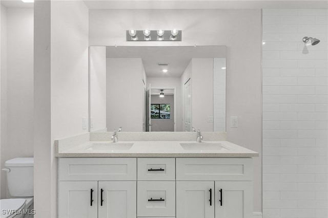 bathroom with tiled shower, vanity, and toilet