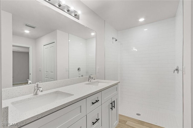 bathroom with tiled shower and vanity