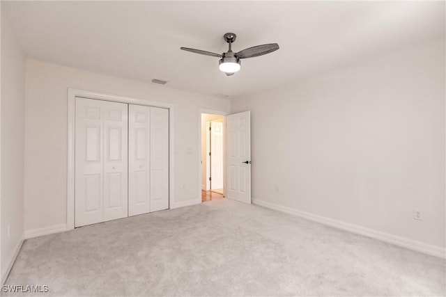 unfurnished bedroom featuring ceiling fan, light colored carpet, and a closet