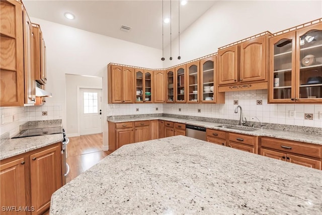 kitchen featuring stainless steel appliances, decorative backsplash, high vaulted ceiling, light stone counters, and sink