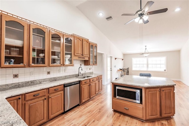 kitchen with stainless steel appliances, decorative backsplash, and light stone countertops