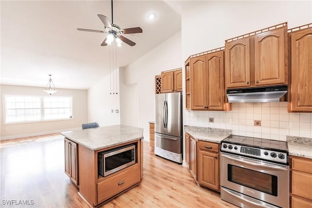 kitchen with stainless steel appliances, backsplash, vaulted ceiling, light stone counters, and light hardwood / wood-style flooring