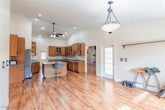 kitchen featuring stainless steel fridge, ceiling fan, a center island, hanging light fixtures, and sink