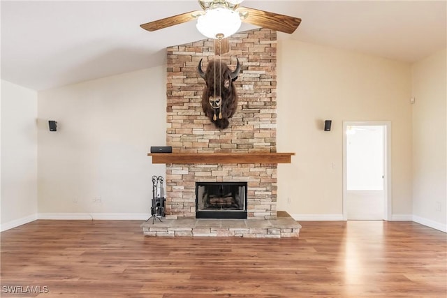 unfurnished living room with lofted ceiling, ceiling fan, a stone fireplace, and hardwood / wood-style floors