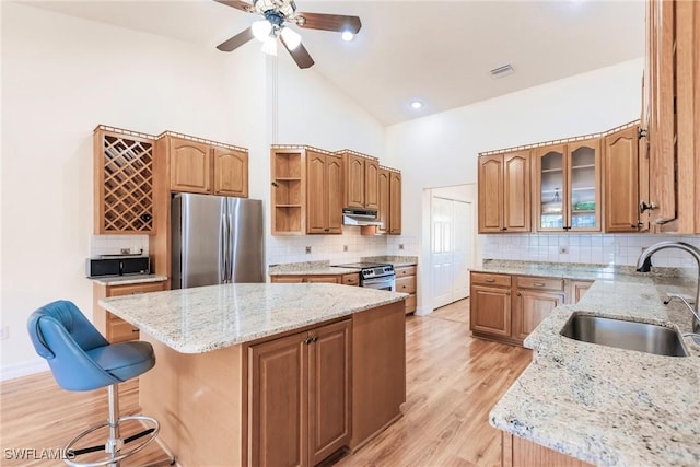 kitchen with stainless steel appliances, high vaulted ceiling, a kitchen island, a breakfast bar, and sink