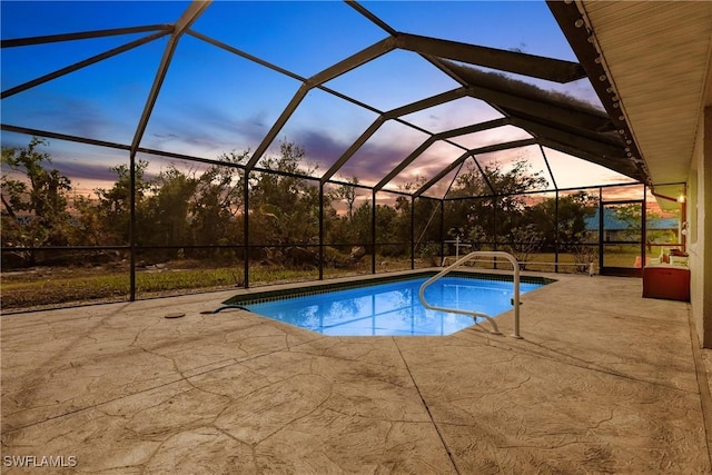 pool at dusk with a lanai and a patio area