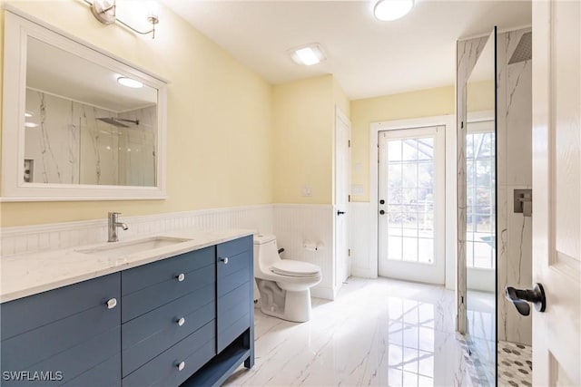 bathroom with toilet, a tile shower, and vanity