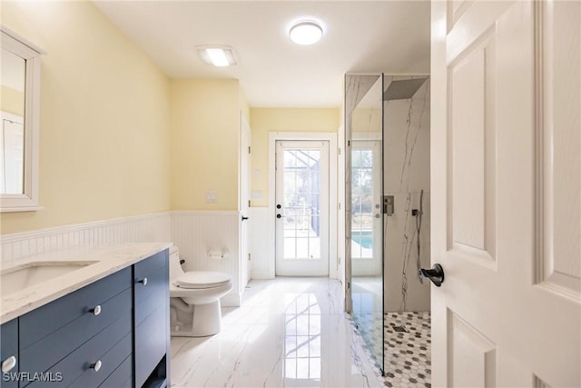 bathroom with toilet, tiled shower, and vanity