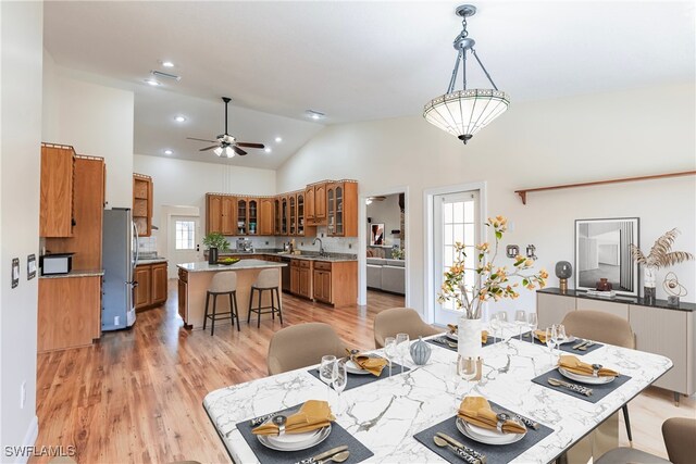 dining space featuring ceiling fan, high vaulted ceiling, sink, and light hardwood / wood-style floors