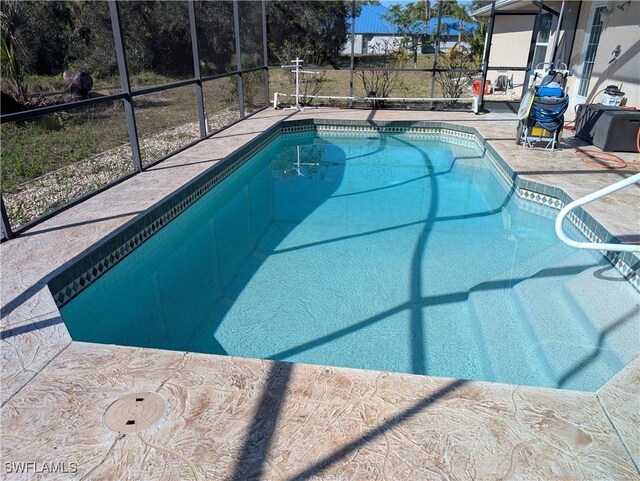 view of swimming pool featuring a patio and glass enclosure