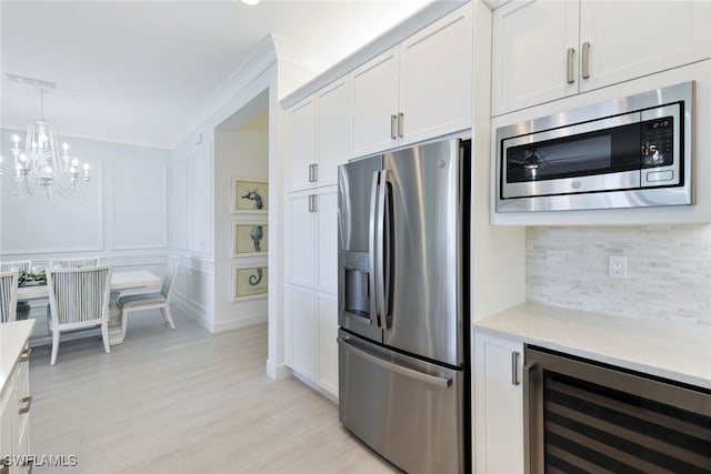 kitchen featuring light stone countertops, appliances with stainless steel finishes, beverage cooler, pendant lighting, and white cabinets