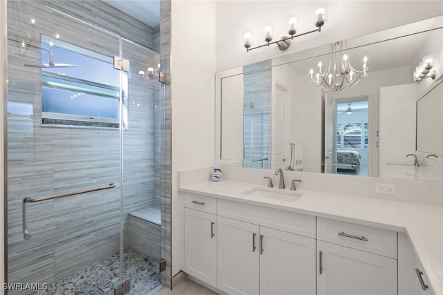 bathroom with vanity, walk in shower, and ceiling fan with notable chandelier