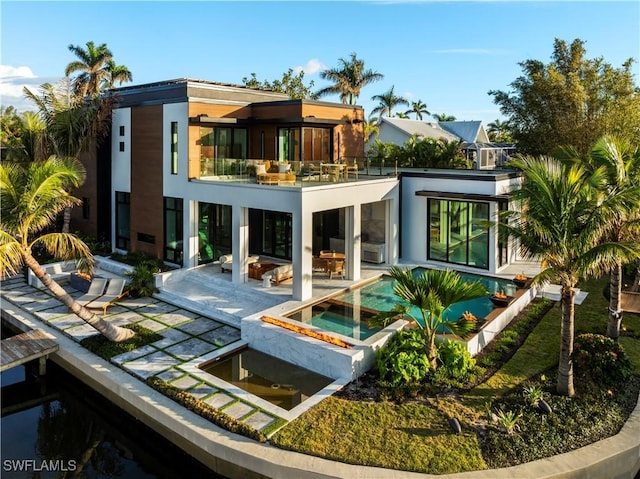 back of house featuring a patio, a balcony, and a pool with hot tub