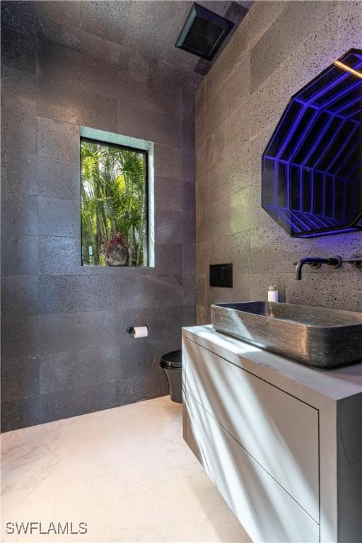 bathroom with vanity, tile walls, and toilet