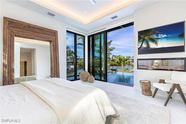 bedroom with access to outside and a raised ceiling
