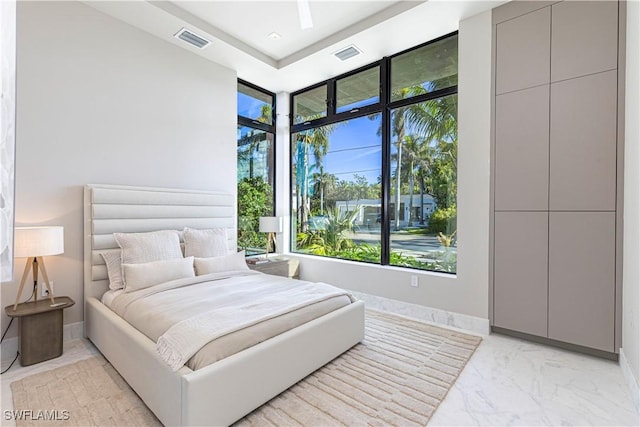 bedroom featuring light marble finish floors, multiple windows, and baseboards