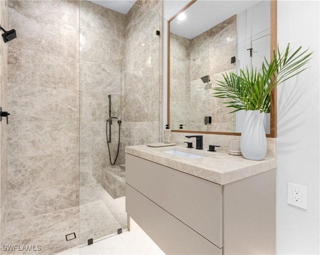 full bathroom with a tile shower and vanity