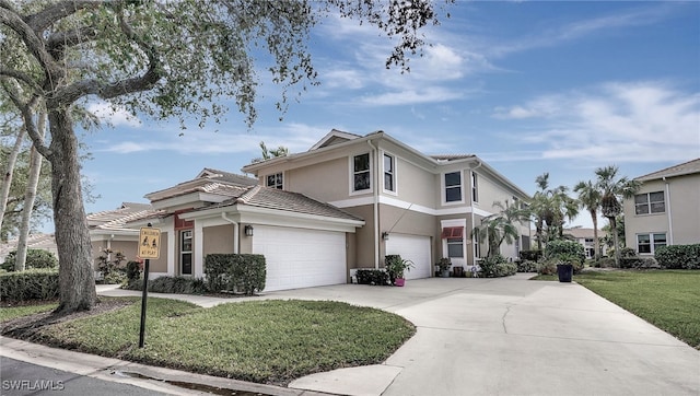 view of front of home with a front lawn, a tiled roof, concrete driveway, and stucco siding