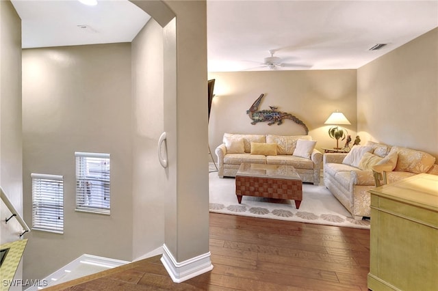 living room with visible vents, baseboards, arched walkways, a ceiling fan, and wood-type flooring