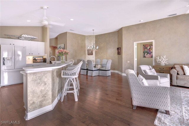 kitchen with dark wood-type flooring, white cabinets, a kitchen breakfast bar, hanging light fixtures, and refrigerator with ice dispenser