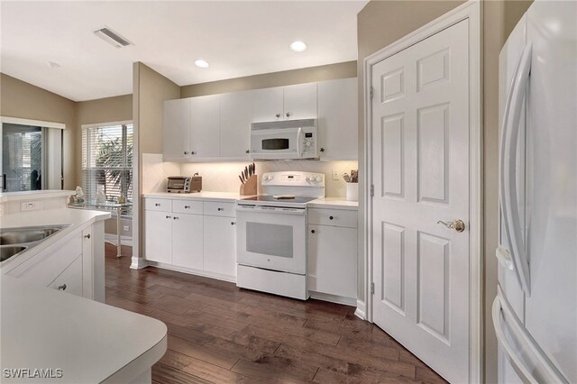 kitchen featuring tasteful backsplash, white cabinetry, dark wood-type flooring, and white appliances