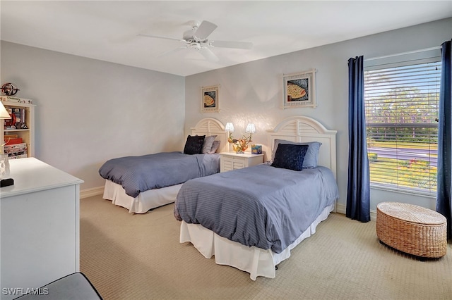 bedroom featuring light colored carpet, a ceiling fan, and baseboards