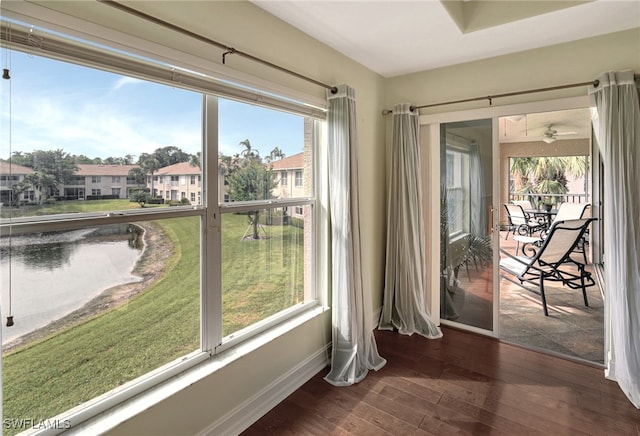 doorway featuring ceiling fan, baseboards, a healthy amount of sunlight, and wood finished floors