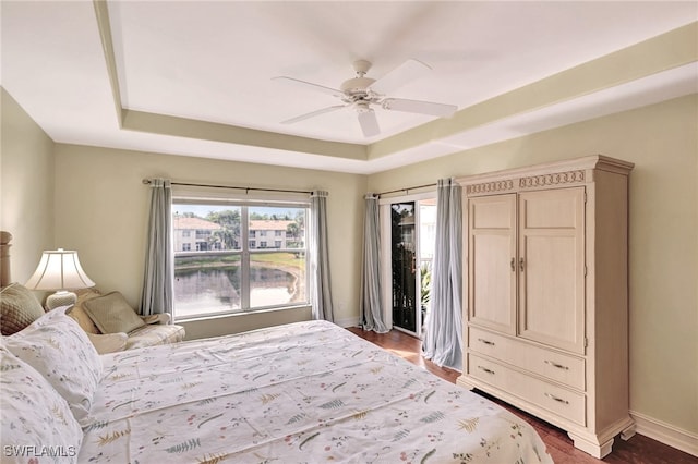 bedroom with a tray ceiling, ceiling fan, and dark hardwood / wood-style floors