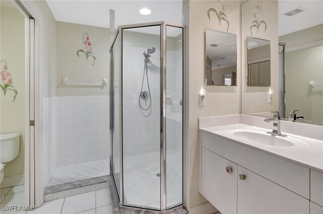 bathroom featuring tile patterned flooring, vanity, toilet, and a shower with shower door