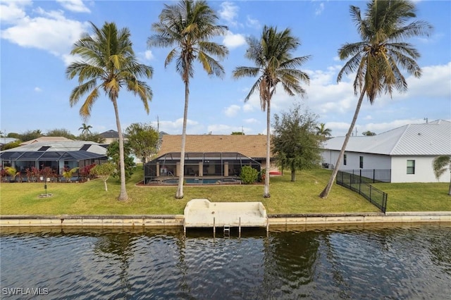 rear view of house featuring glass enclosure, a water view, and a yard